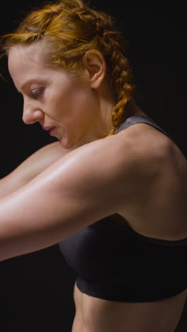 Vertical-Video-Studio-Shot-Of-Mature-Woman-Wearing-Gym-Fitness-Clothing-Doing-Stretching-Exercises